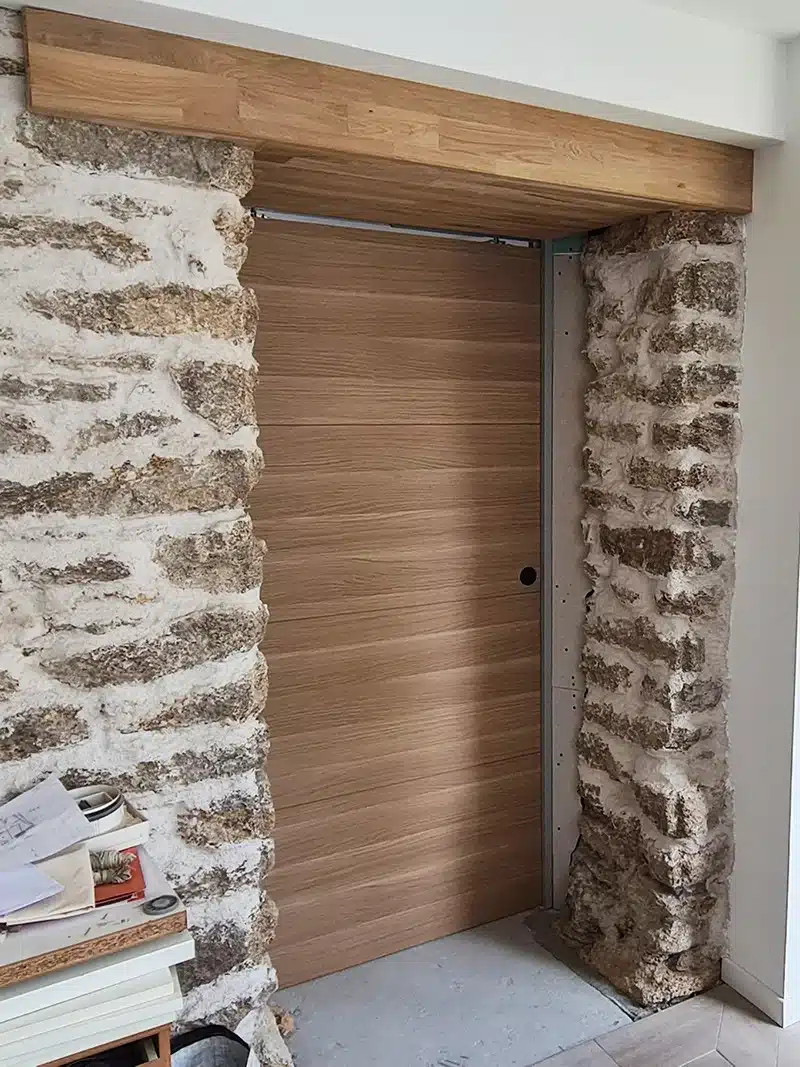 Detail design porte à galandage bois et mur de pierre